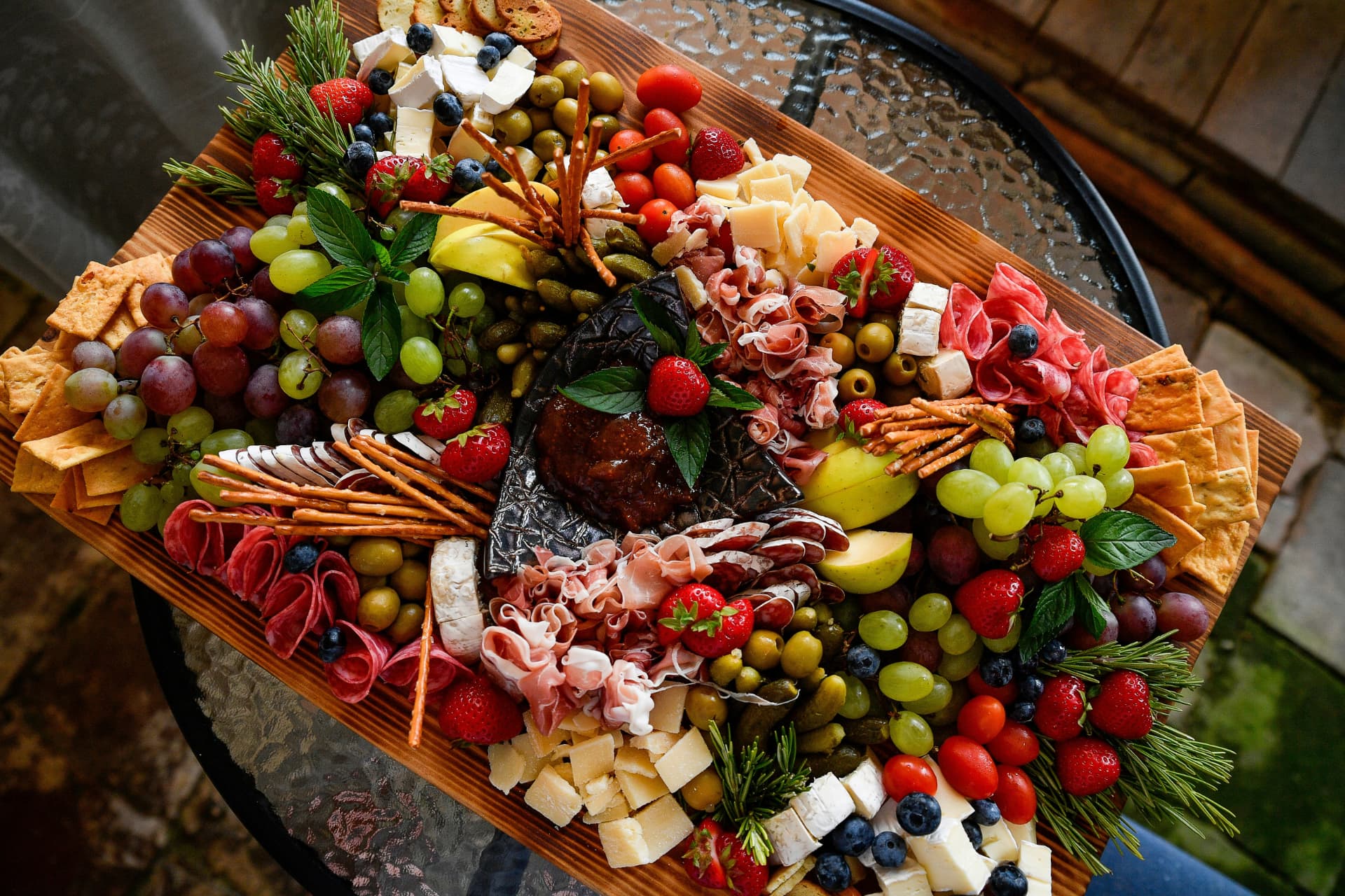 Abundant outdoor grazing board filled with cheeses, cured meats, fruit, olives and crackers