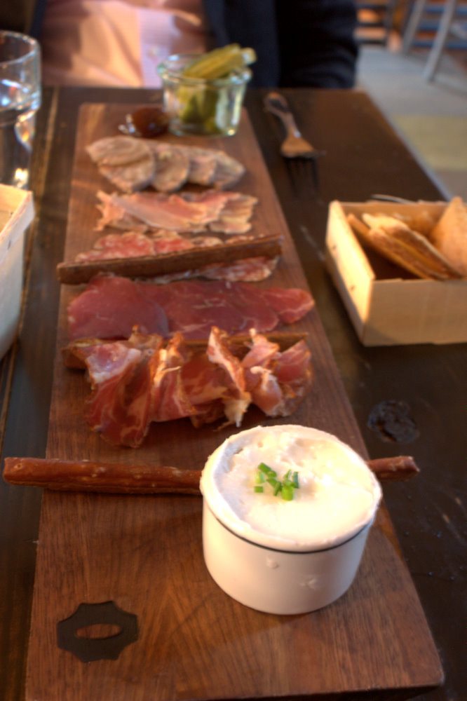 Long wooden charcuterie board with cured meats and accompaniments