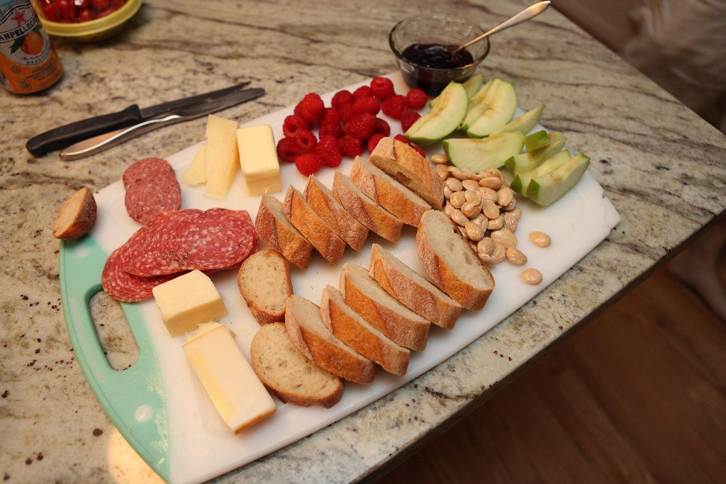 Charcuterie board with salami, cheeses, bread, fruit and nuts
