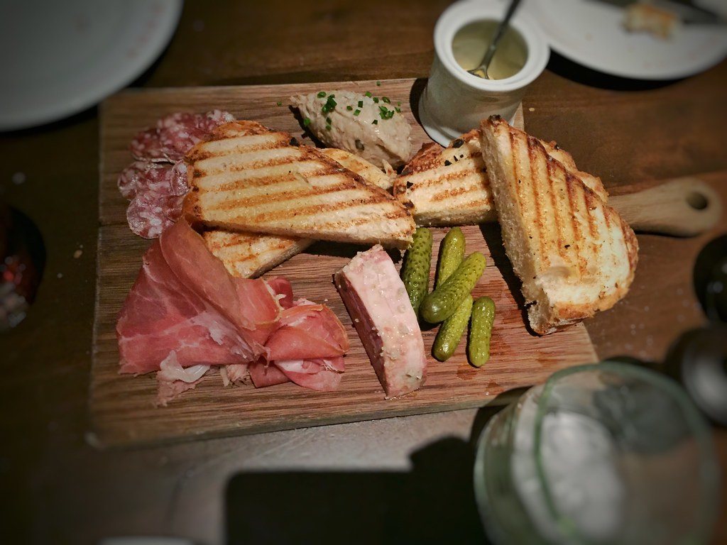 Charcuterie board with toasted bread, pâté, meats and cornichons
